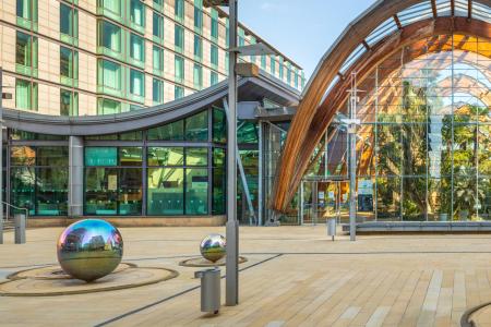 The silver spheres of the Peace Gardens stand before the impressive wooden arch of the Winter Garden in the early morning sun.